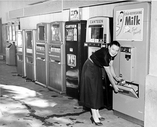 Woman using milk vending machine in 1940s